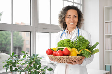 Poster - Mature female nutritionist with healthy vegetables and tape measure in office