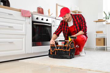 Wall Mural - Male technician with bag of tools repairing oven in kitchen