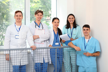 Poster - Group of young doctors with clipboards on stairs in clinic