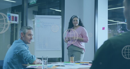 Wall Mural - Image of web globe icons floating against biracial woman giving a presentation at office