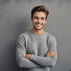 Portrait of happy young man leaning against wall isolated on grey background with a big smile. Handsome cheerful guy in winter clothes on gray wall looking at camera. Stylish man wearing sweater with 