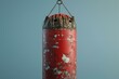 © ylivdesign - Old, worn out red punching bag is hanging in front of a blue background