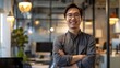 © chutikan - Asian businessman standing with arms crossed and smiling with confidence at modern office
