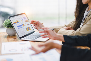 two professional analyzing financial data graphs, charts on laptop display at a modern workspace. fi