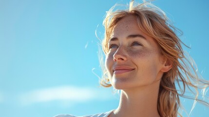 Wall Mural - Fit blonde woman smiles while deep breathing in front of a clear blue sky on a sunny and windy summer day