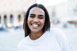 © Davide Angelini - Portrait picture of young black woman smiling at camera outside - Happy african female walking in city street - People life style concept