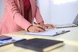 © Worapon - Image of a young Asian female company employee smiling and holding a digital tablet standing on a white background.