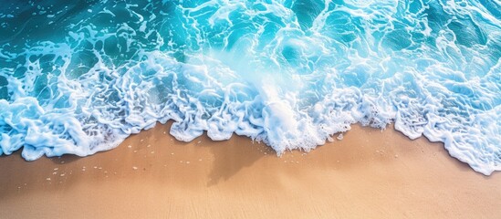Wall Mural - Top view summer beach scene with sea waves, sandy shore, and foam: ideal background for vacation concept with space for text.