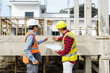 © Phushutter - Two male construction workers, including an Asian engineer, meticulously review structural plans and design concrete columns and beams for a new residential build.