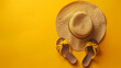 © Vivid_Vision - A beach hat and a pair of sandals on a bright yellow background.