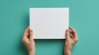 © Wahyu - Hands Holding a Blank White Square Paper on a Turquoise Background
