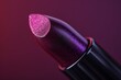 © Mind - Close-up of a vibrant purple lipstick on a dark background, showcasing its smooth texture and rich color perfect for bold makeup looks.