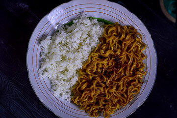 Plates of rice and instant noodles on a black background. Unhealthy combination of carbohydrates.