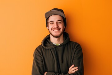 Wall Mural - a cheerful young man in his twenties with a cap and hoodie, against a solid olive background