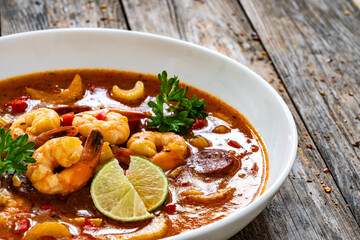 Wall Mural - Louisiana soup gumbo with shrimp, chorizo and white rice served in white plate on wooden table
