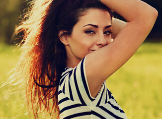 Wall Mural - Beautiful young woman looking happy with long hair on nature summer background. Closeup