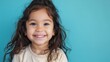 © M.IVA - Portrait of a Happy and Playful Little Girl with a Joyful Smile Against a Blue Background