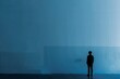 © Oskar Reschke - lone figure standing against a solid blue wall, their silhouette outlined by soft backlighting that creates a contemplative atmosphere, with minimalist composition and monochromatic palette conveying