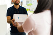 © AntonioDiaz - Closeup of a delivery man delivering medication in a white box with the word pharmacy on it to a woman