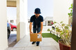 © AntonioDiaz - Delivery man in uniform carefully drops off a package at a house entrance, showcasing the importance of efficient logistics in online shopping