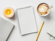 © qorqudlu - A serene top-down view of a white desk arranged with a spiral notebook, a cup of cappuccino with latte art, a pencil, and a lit candle, showcasing a minimalist workspace.