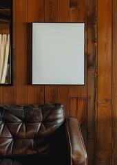 Wall Mural - A modern interior featuring a sleek dark leather couch beneath a blank framed picture, set against a backdrop of rich, wooden paneled walls, exuding elegance and style.