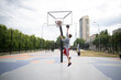 © Mihail - man in a grey hoodie and red shorts prepares to execute a basketball layup on an outdoor court. The basketball is about to enter the hoop