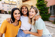 © Xavier Lorenzo - Smiling portrait of small group of three young women laughing at camera standing together at picturesque village during summer vacation. Holiday lifestyle and friendship concept