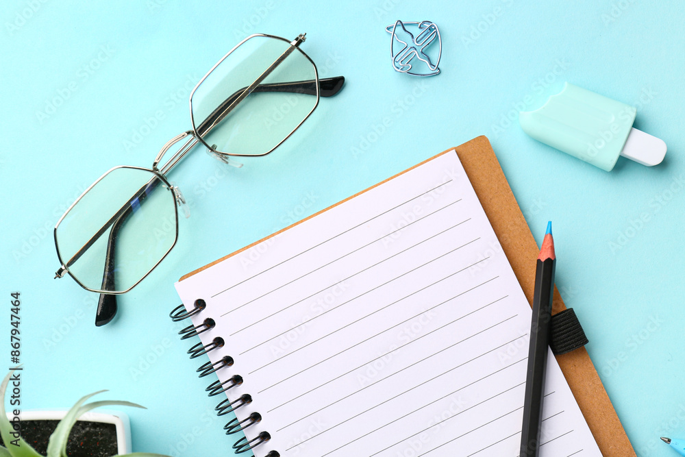 Set of stationery, glasses and notebook on cyan background