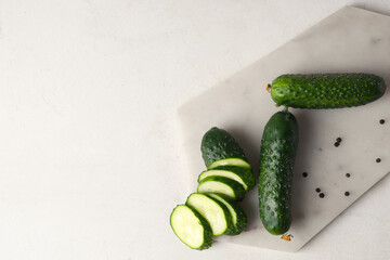 Wall Mural - Board with fresh green cucumbers and peppercorn on white background