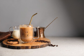 Wall Mural - Glass cup of iced latte with sweet cookies and coffee beans on white background