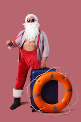 Wall Mural - Santa Claus with suitcase and ring buoy on pink background. Christmas in July