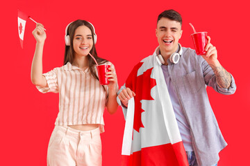 Canvas Print - Young couple with flags of Canada and soda on red background