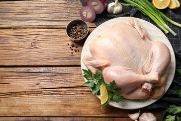 Wall Mural - Fresh raw chicken with different products on wooden table, flat lay. Space for text