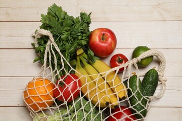 Sticker - Vegan food delivery. Net bag with different fresh vegetables and fruits on light wooden background, flat lay