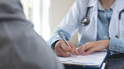 Female doctor writing a prescription for her patient. Docotr filling medical insurance claim form at medical clinic, healthcare and medicine concept, close up