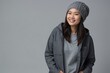© Cristian - Asian woman with smile on her face next to empty space on dark gray background. Beautiful young woman in stylish clothes in a studio with place for advertising text.