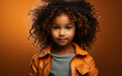© imagineRbc - A young Black girl with curly hair is wearing a brown jacket and standing against an orange background. She is looking directly at the camera with a serious expression