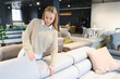 © Serhii - Portrait of young cheerful woman testing sofa in furniture store
