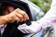 © Andrey Popov - Luxury chauffeur service at a hotel: a businessperson's hand giving car key