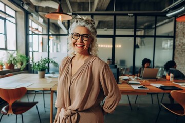 Wall Mural - Mature businesswoman smiling happily in an office Happy mature businesswoman smiling at the camera while standing in an office. Cheerful mature businesswoman standing in the boardroom of a modern work