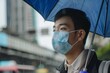 © alisaaa - Gentleman with in coronavirus infected city holding umbrella on rainy day One man, young Taiwanese businessman downtown in Taipei, holding blue umbrella and wearing a pollution mask