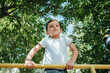 © alexkoral - child boy playing and climbing on horizontal bars on the playground in summer