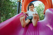 © alexkoral - happy child kindergarten boy playing on a slide on the playground in summer