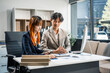 © NanSan - A businessman and businesswoman work late in the office, discussing strategies at a desk. They use technology and teamwork to plan and achieve success, demonstrating effective communication.