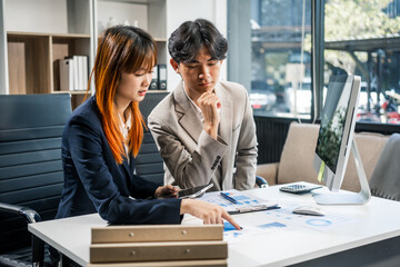  A businessman and businesswoman work late in the office, discussing strategies at a desk. They use technology and teamwork to plan and achieve success, demonstrating effective communication.