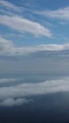 Wall Mural - aerial view. blue sky sun and fog over calm sea. the drone flies over foggy and fluffy clouds. abstr