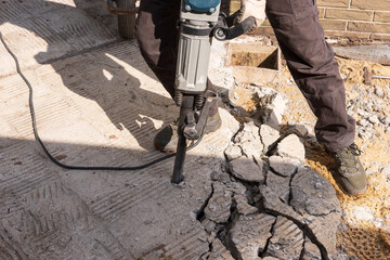 Construction work. Construction worker chisels the concrete slab with a hammer drill