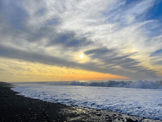 Wall Mural - sunset on the seashore. empty beach, black sand, sea wave, sun and sky cloud background