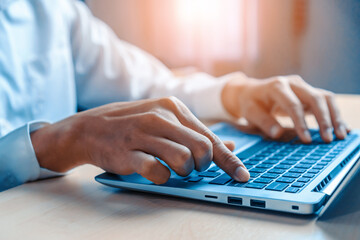 Wall Mural - businessman hand typing on computer keyboard of a laptop computer in office. business and finance co